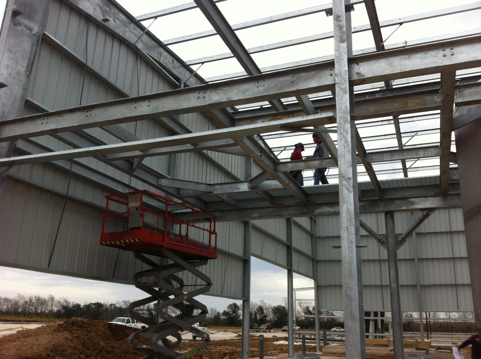 Galvanized mezzanine framing under construction with scissor lift